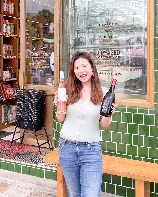 Priscilla outside a Hong Kong deli holding two bottles of wine