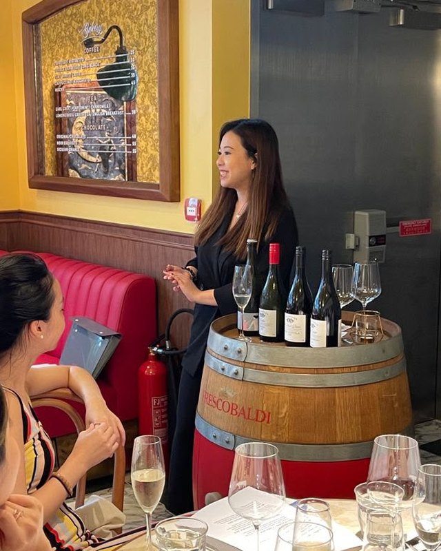 Priscilla hosting a wine tasting for a table of guests